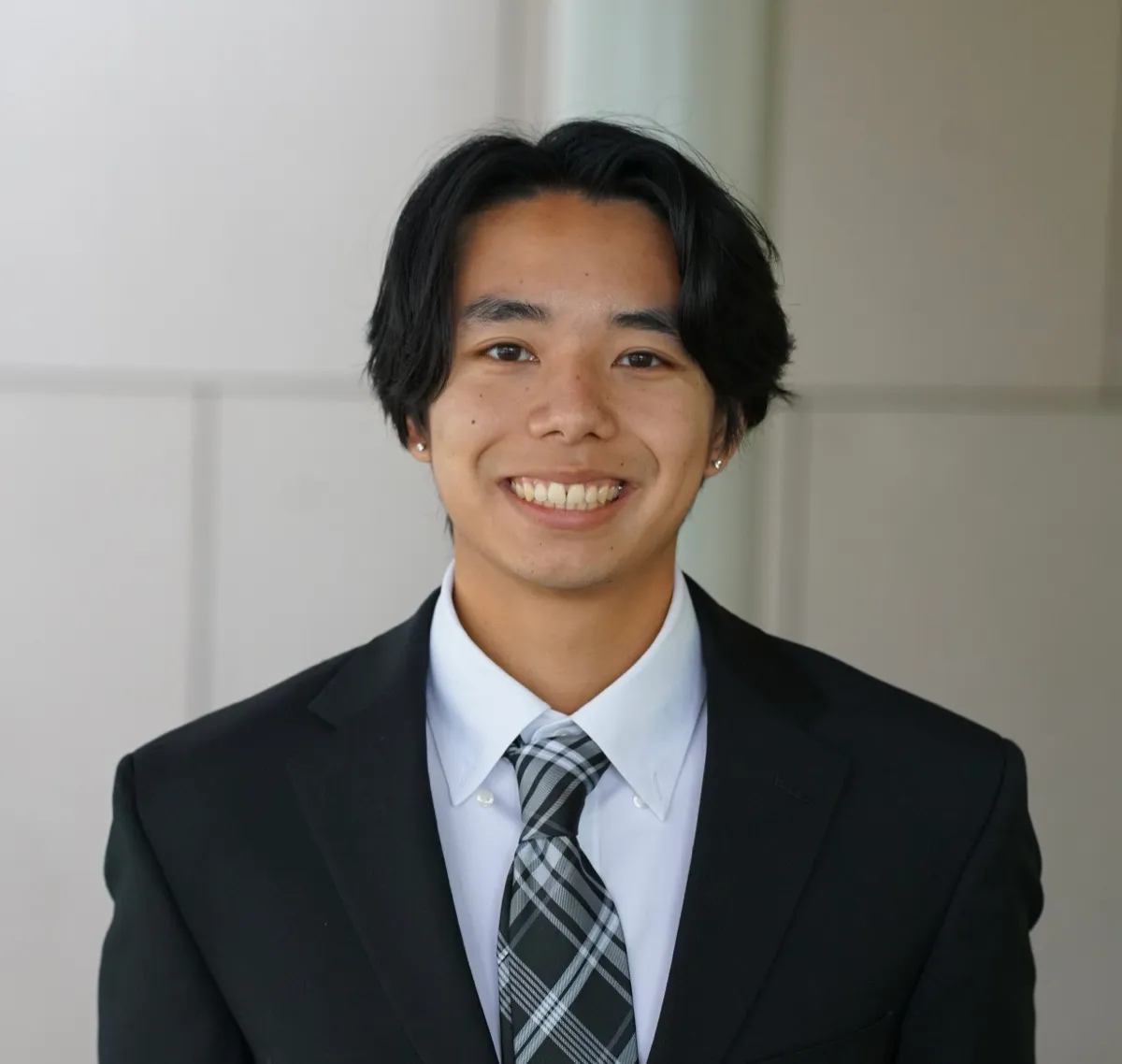 Leland Nguyen smiling, wearing a dark suit and plaid tie